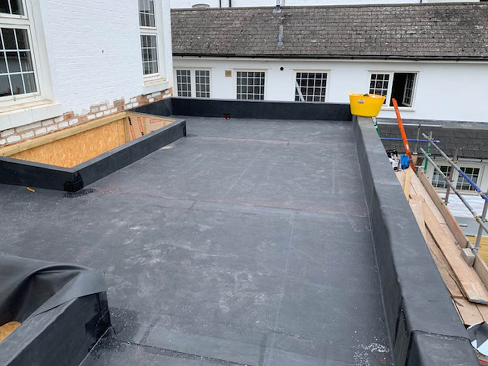 Newly installed EPDM rubber flat roof on a large commercial building with scaffolding in place